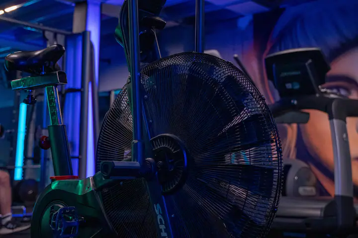 Fan air bike in a gym lit with blue neon