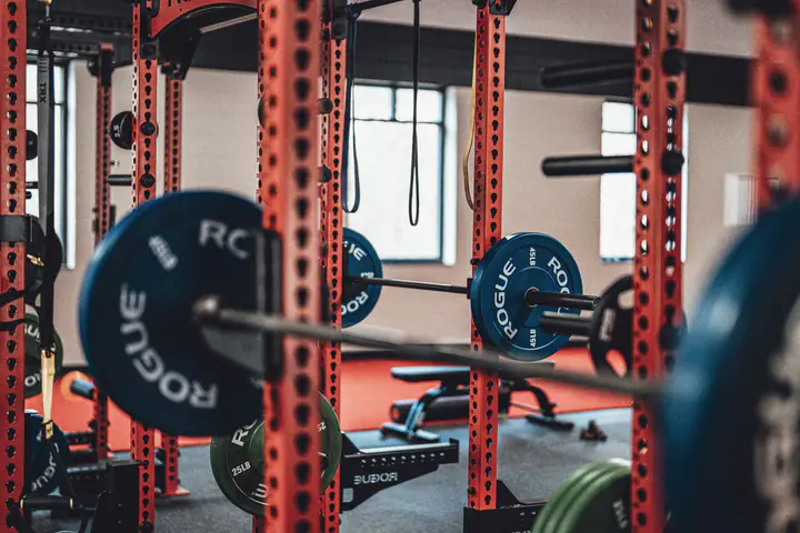 Barbell loaded with bumper plates set in a red power rack