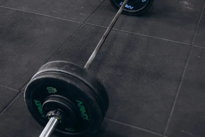 Loaded barbell lying on a rubber floor in a strength and conditioning gym