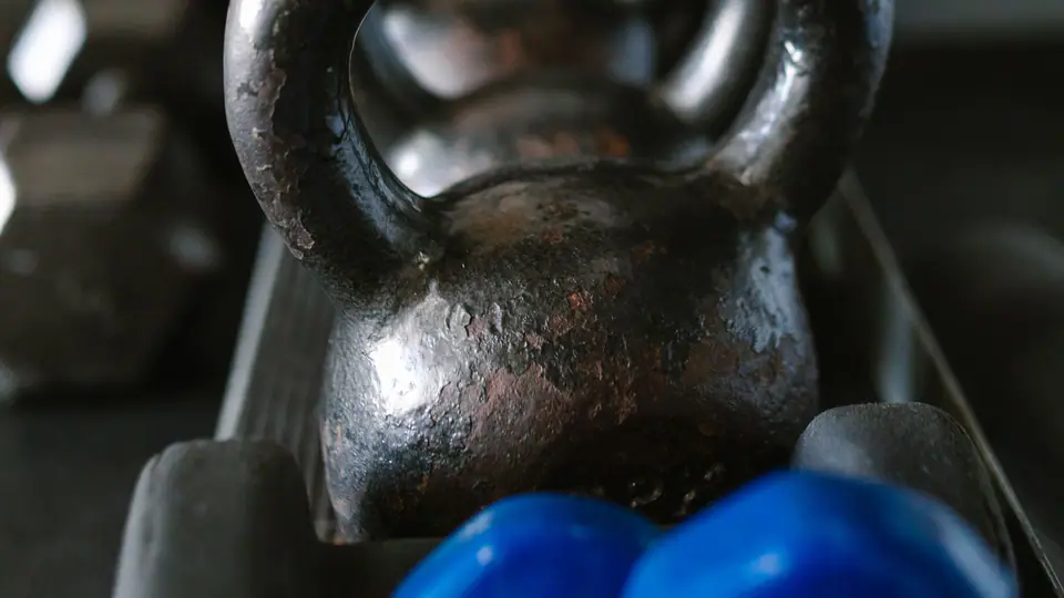 Kettlebell on a storage rack with blue dumbbells below