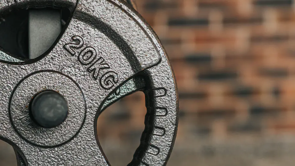 Stack of 20 kg cast-iron weight plates against a brick wall
