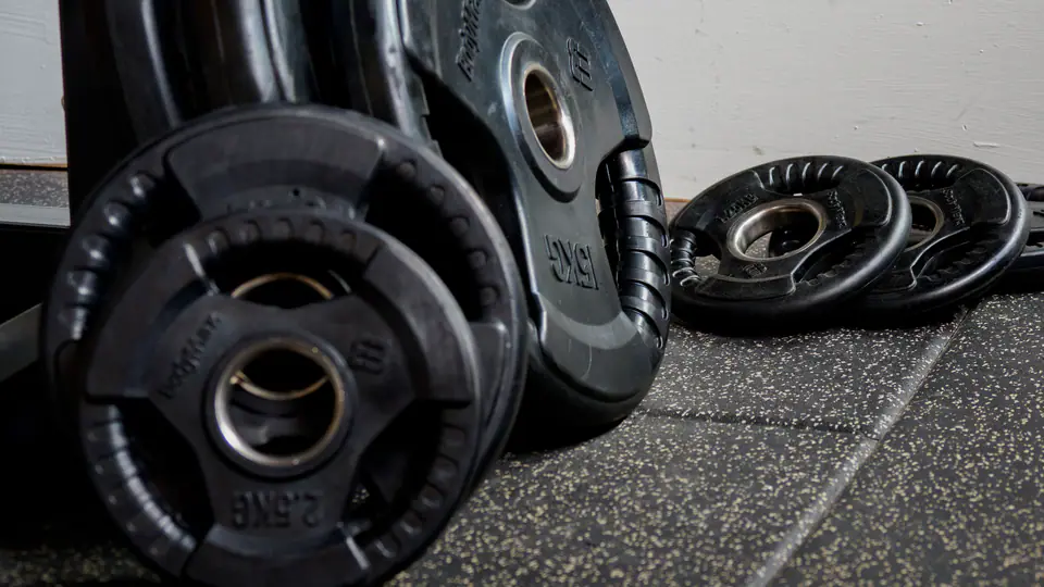 Rubber-coated weight plates leaning on a rubber gym floor