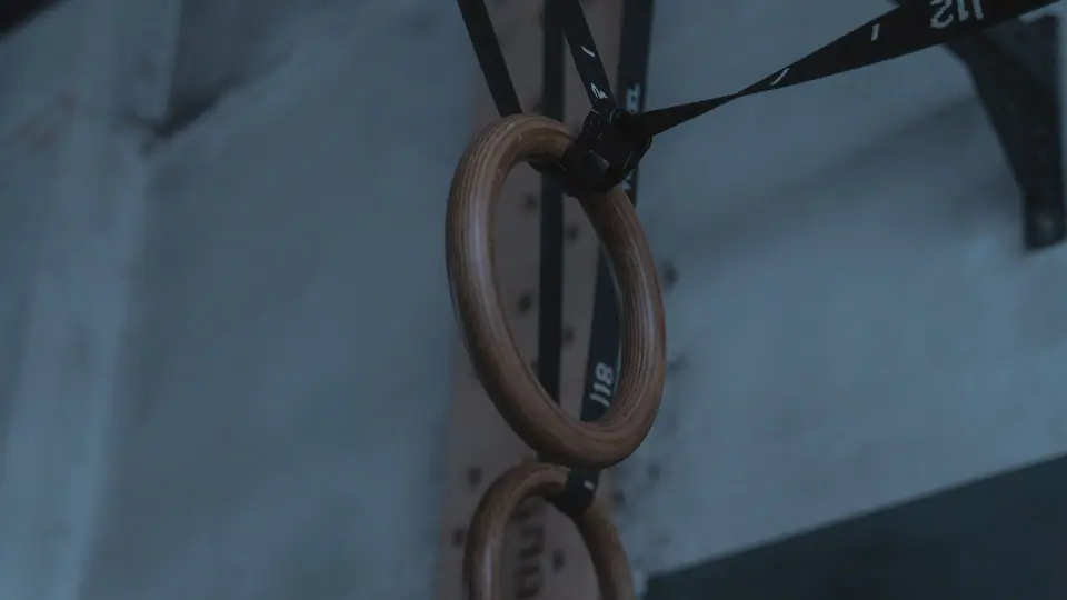 Wooden gymnastic rings hanging on straps in a gym