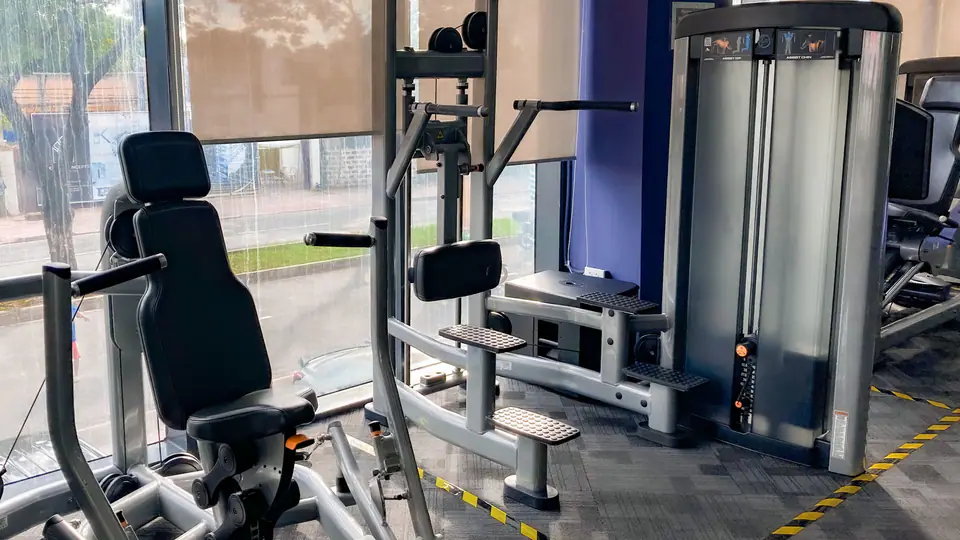Assisted dip and pull-up machine beside a chest press in a gym by the window