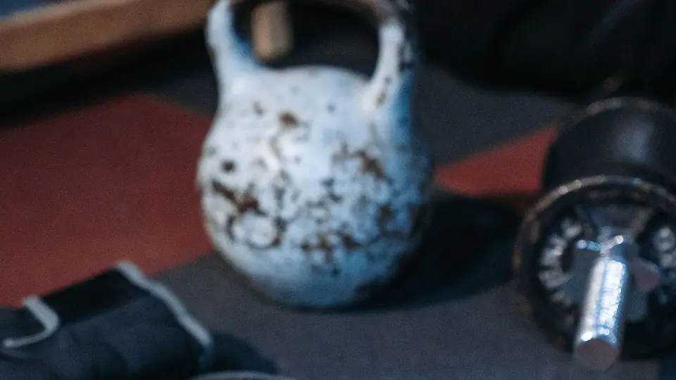 Kettlebell, boxing gloves and a dumbbell on a red and black gym floor