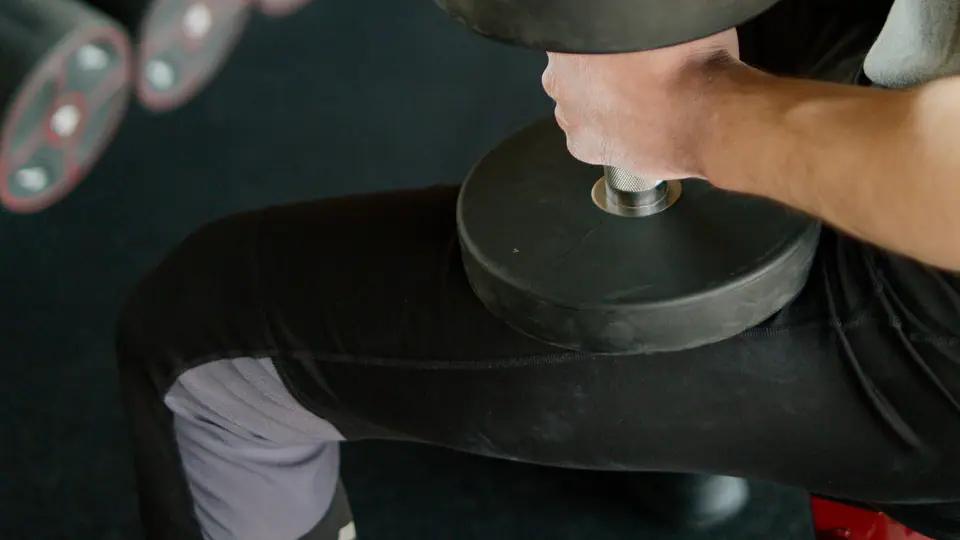 Lifter seated on a bench with a heavy dumbbell resting on his knee