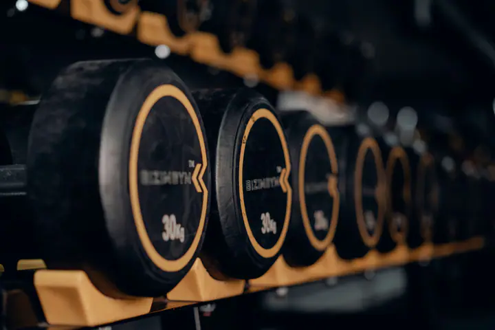 Dark rack of round dumbbells with gold weight numbers