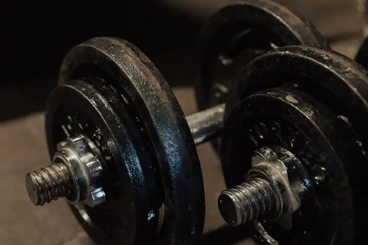 Pair of spin-lock dumbbells on the floor at the foot of a bed