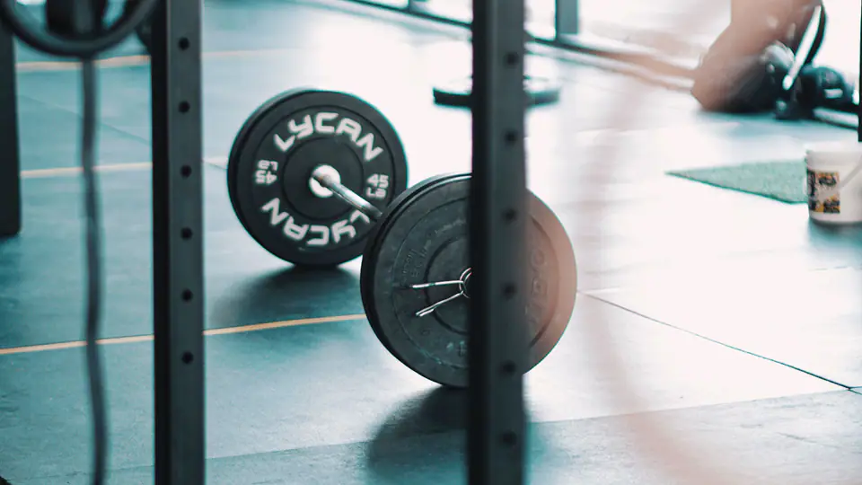 Loaded barbell on a lifting platform, seen between the uprights of a rack