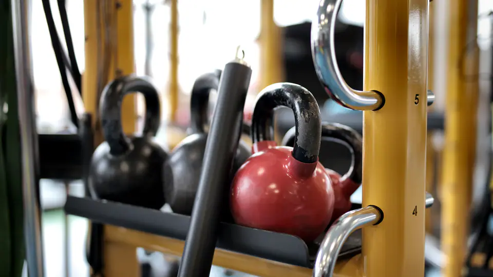 Kettlebells stored on a yellow rack in a gym