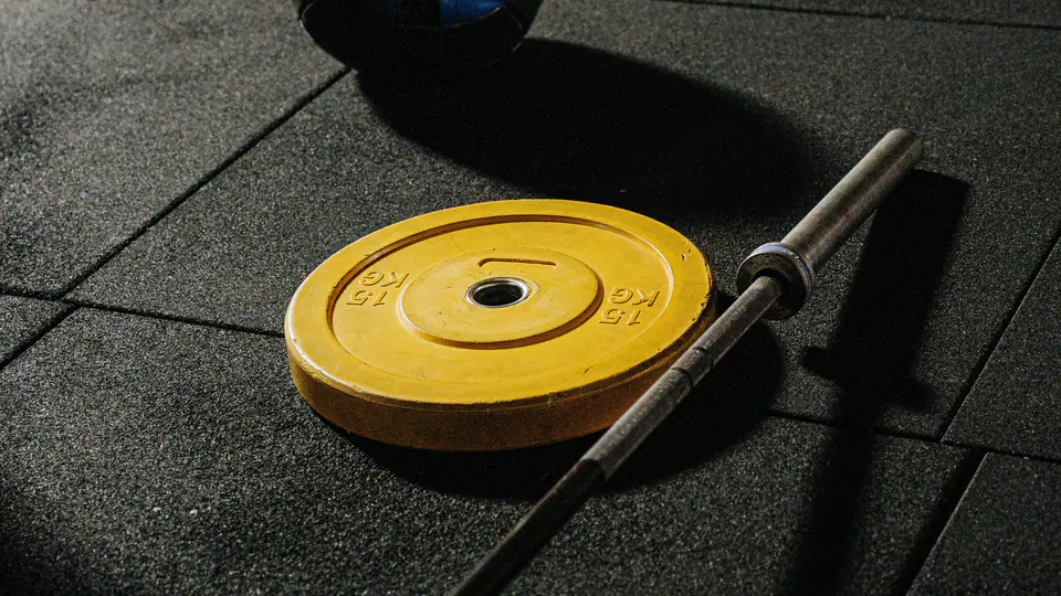 Medicine ball, a yellow bumper plate and a barbell on a rubber gym floor