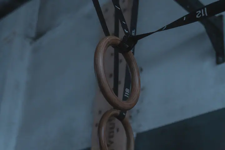 Wooden gymnastic rings hanging on straps in a gym