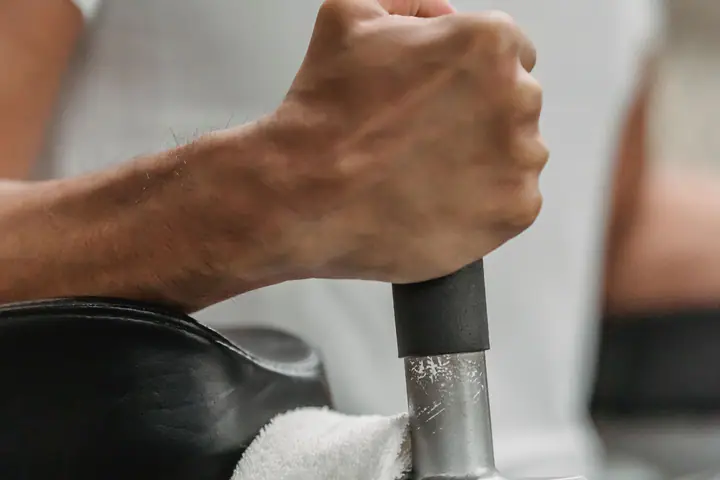 Lifter gripping a machine handle, with a towel laid over the seat
