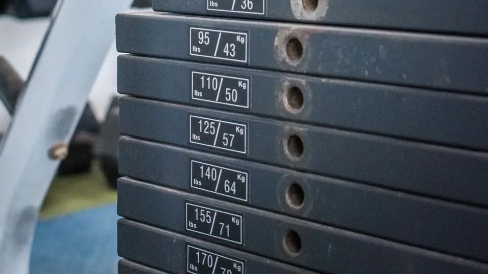 Weight stack of a cable machine with the selector pin set in one of the numbered plates