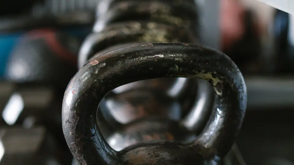Kettlebell on a storage rack with blue dumbbells below