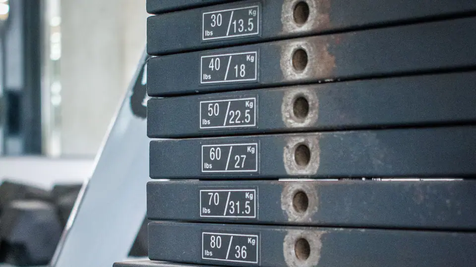 Weight stack of a cable machine with the selector pin set in one of the numbered plates