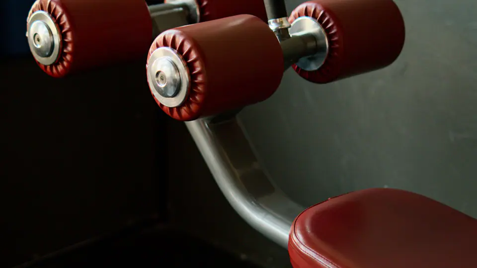 Decline sit-up bench with red padded foot rollers