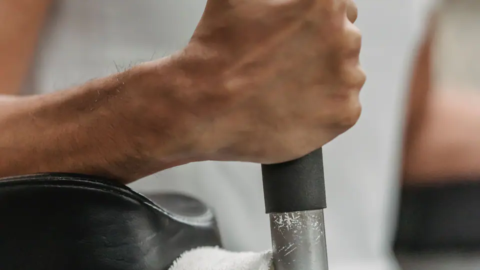 Lifter gripping a machine handle, with a towel laid over the seat