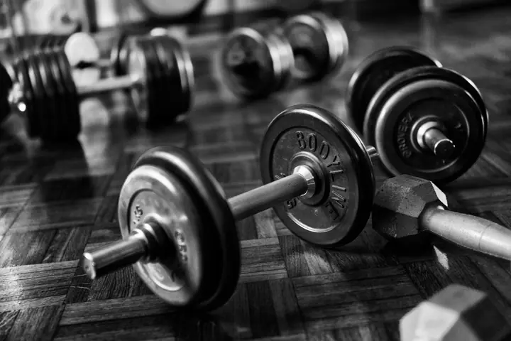 Black-and-white photo of spin-lock dumbbells on a wooden gym floor