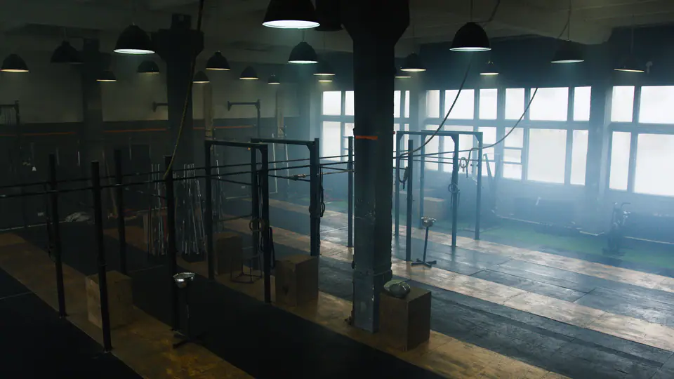 Pull-up rigs in a large industrial gym with mist and morning light through the windows