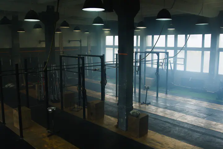Pull-up rigs in a large industrial gym with mist and morning light through the windows