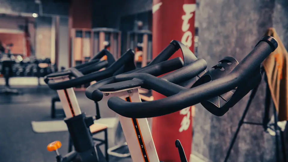Indoor cycling bikes lined up in front of a heavy punching bag