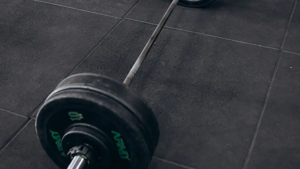 Loaded barbell lying on a rubber floor in a strength and conditioning gym