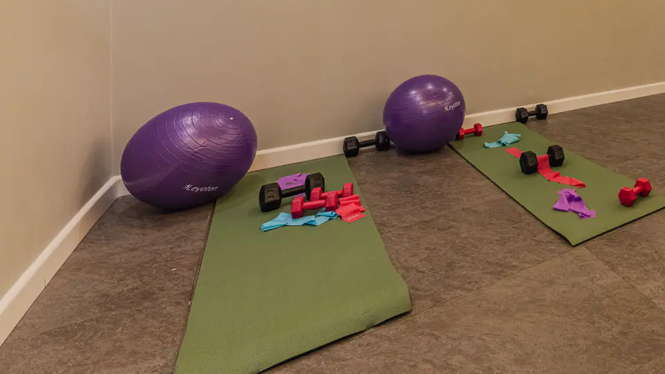 Small home workout room with an exercise bike, yoga mats, stability balls and light dumbbells
