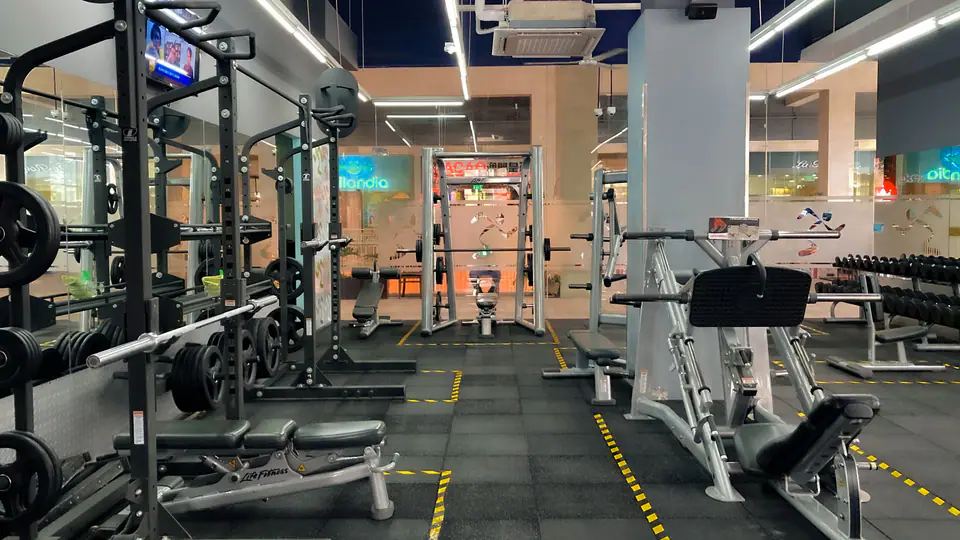 Gym floor with squat racks, a Smith machine and benches
