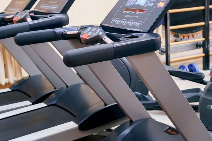 Row of treadmills in a bright gym with a stability ball against the wall bars
