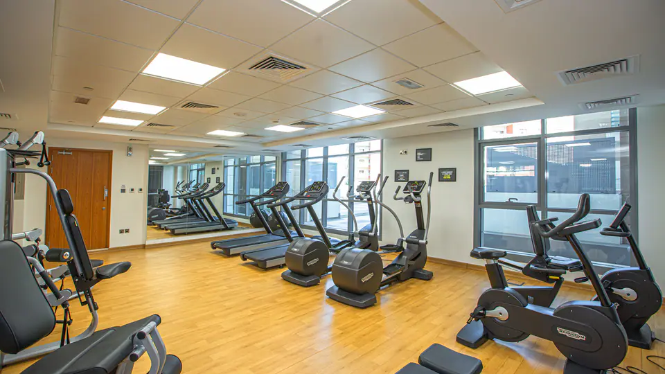 Bright gym with treadmills, cross-trainers and exercise bikes along the windows