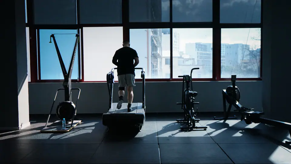 Man walking on a curved treadmill in front of a large window