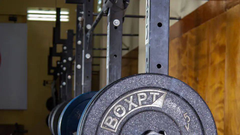 Weight plate on a barbell resting in the uprights of a rack