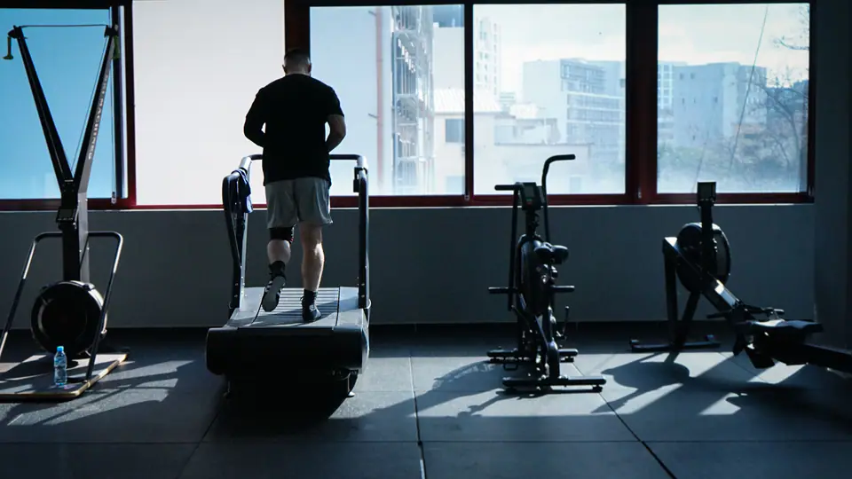 Man walking on a curved treadmill in front of a large window
